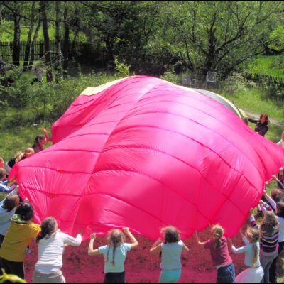 Kinder spielen gemeinsam im Kreis mit einen großen Tuch